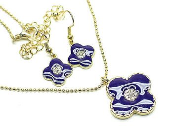 Elegant guldpläterad smyckeset med kristaller och lila färgad enamel blomma